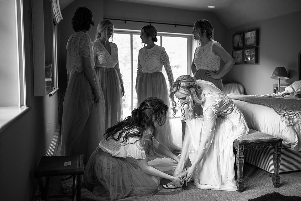 Bride having her shoes put on in black & white